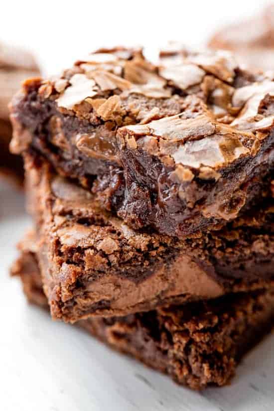 Three chocolate and gooey brownies stacked on top of each other.