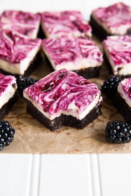 Multiple blackberry cheesecake brownies with blackberries.