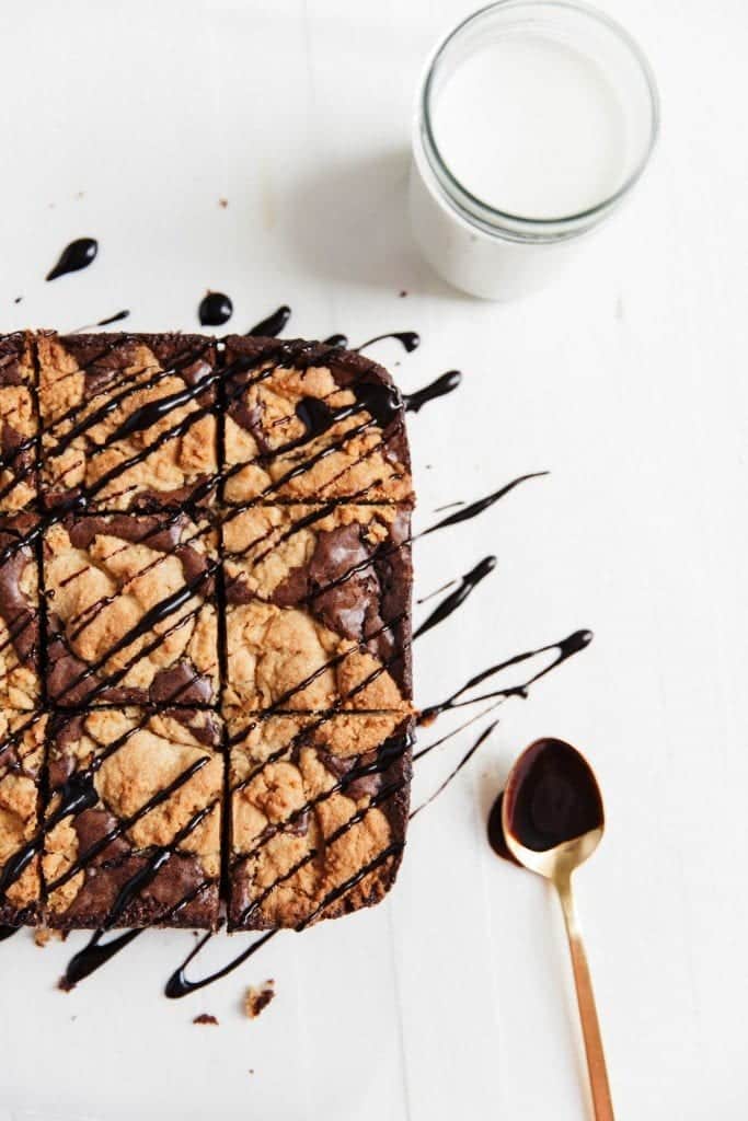 Peanut butter cookie brownies with chocolate sauce and a glass of milk.