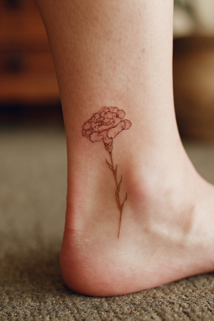Tiny carnation flower tattoo in minimalist outline design.