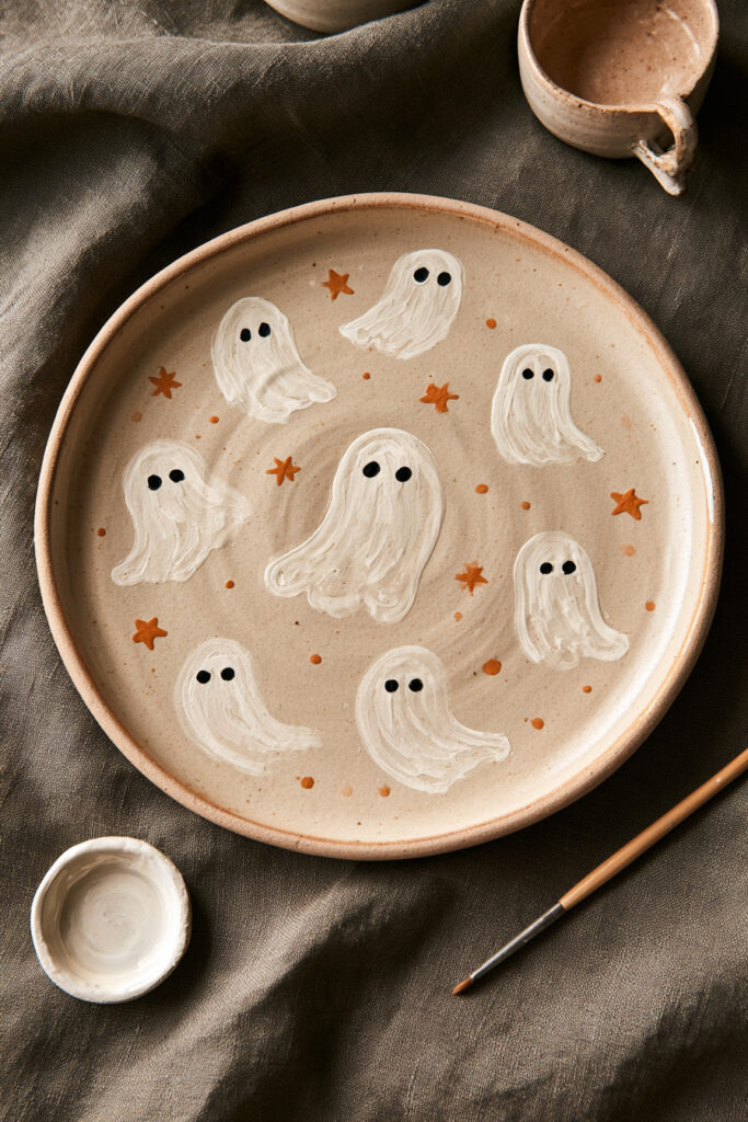 Orange ceramic plate painted with small white ghost shapes and black eyes