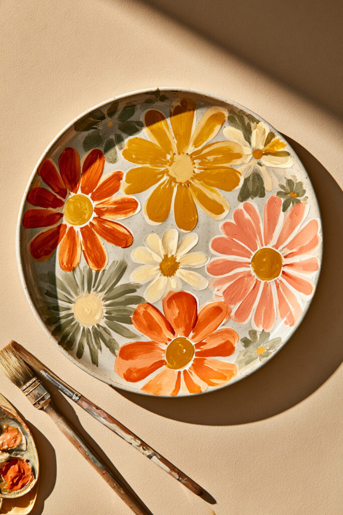 Cream ceramic plate painted with retro orange, pink, and mustard flowers