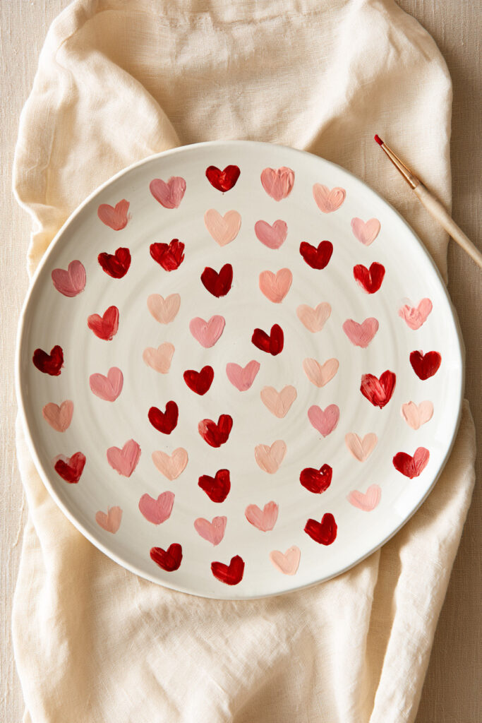 White ceramic plate painted with scattered red and pink hearts